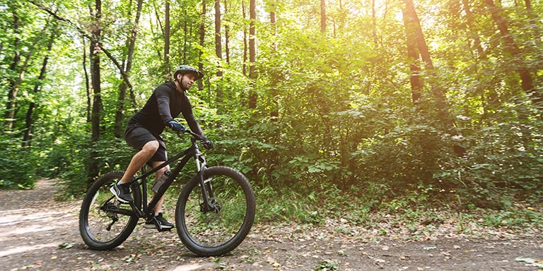 Ein Mann fährt mit einem Mountainbike über einen Waldweg.